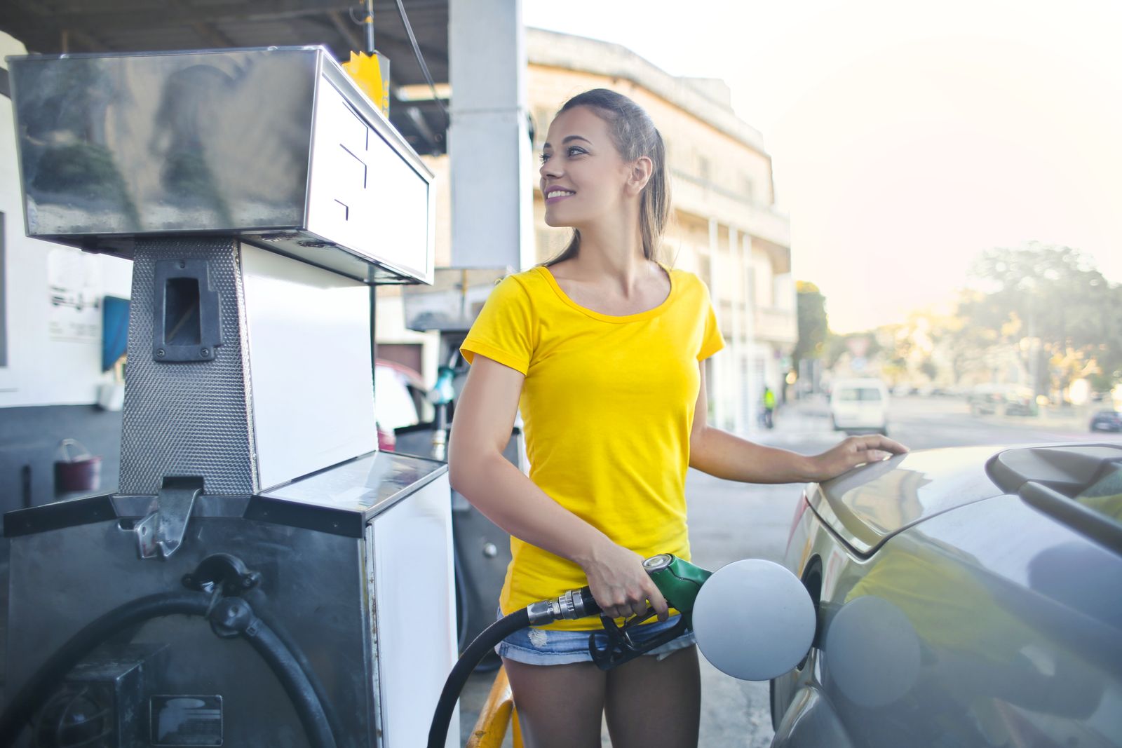Woman in a yellow shirt filling her car at a petrol station