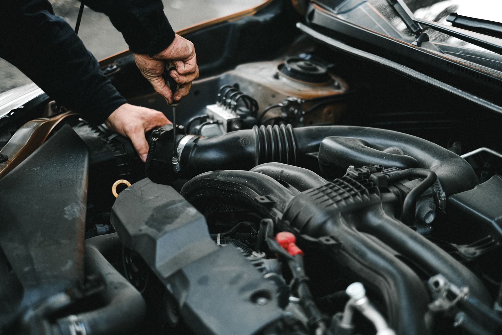 Close-up of hands working on a car engine bay