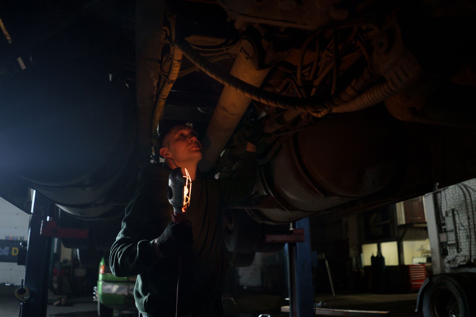 Mechanic inspecting the underside of a vehicle with a torch